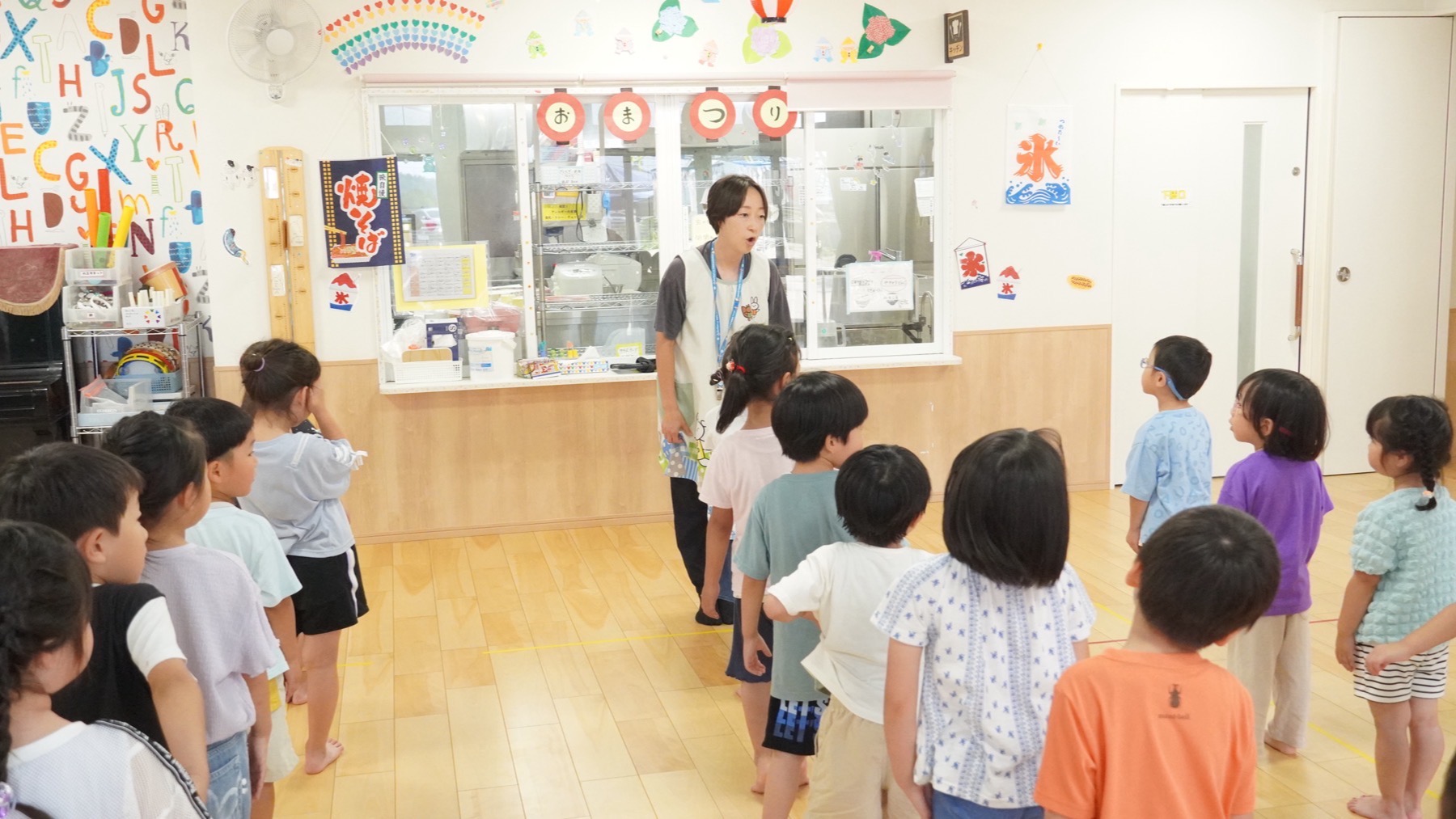朝の会に集まり、保育士の話を聞く3・4・5歳児の子どもたち