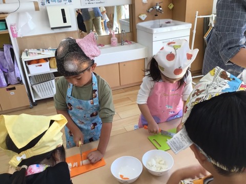 エプロンと三角巾をつけて、包丁で野菜を切る食育教室の子どもたち