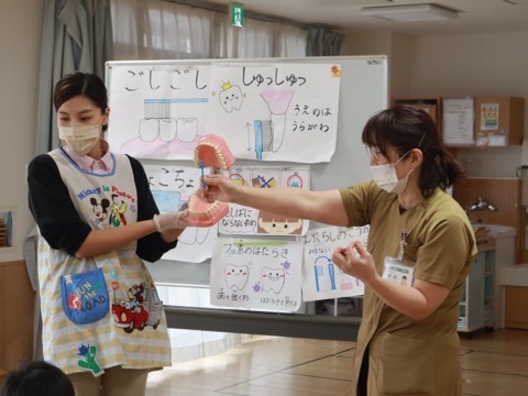 歯の模型と歯ブラシを使って、正しい歯磨きの仕方を子どもたちに教えている様子